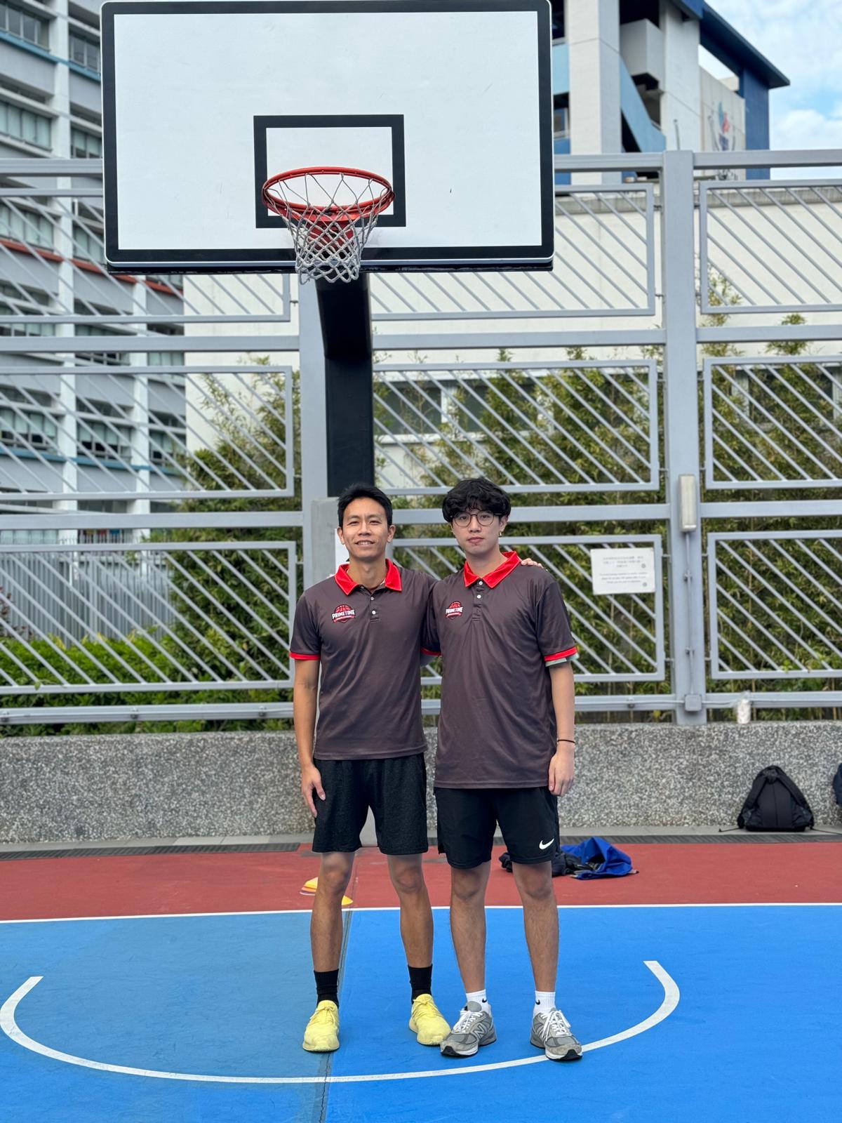 Two men standing in front of a basketball court.